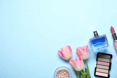 Photo of Flat lay composition with different makeup products and beautiful spring flowers on light blue background, space for text