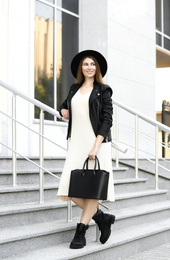 Photo of Beautiful young woman with stylish leather bag outdoors