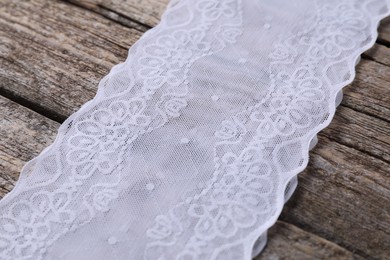 Photo of White lace with pattern on wooden table, closeup