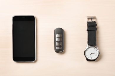 Photo of Flat lay composition with smartphone, wristwatch and remote car key on wooden background. Space for text