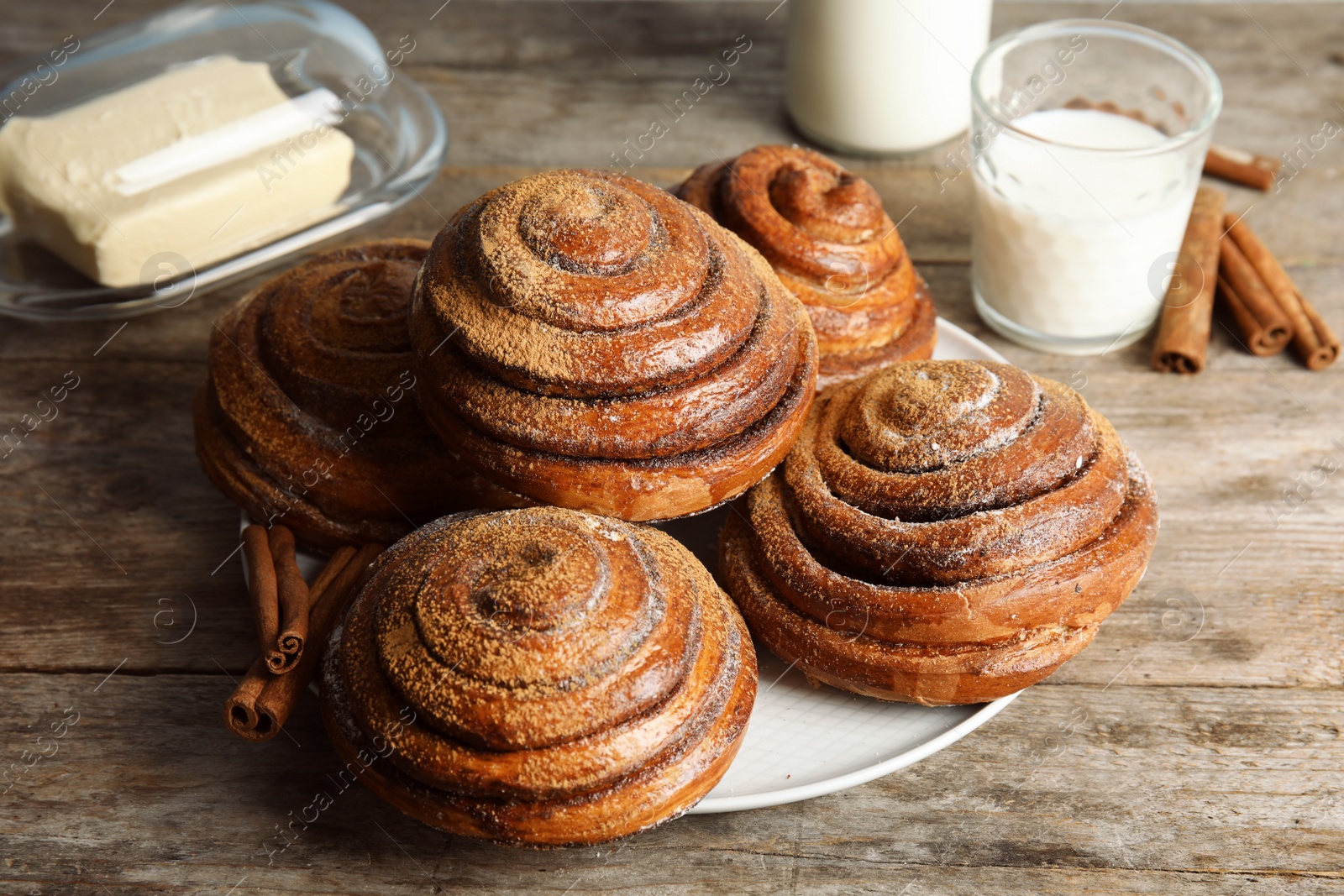 Photo of Plate with baked cinnamon rolls on wooden table