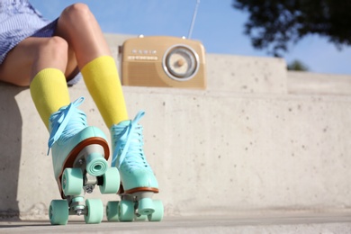 Photo of Young woman with vintage roller skates and radio sitting on stone stairs, closeup view