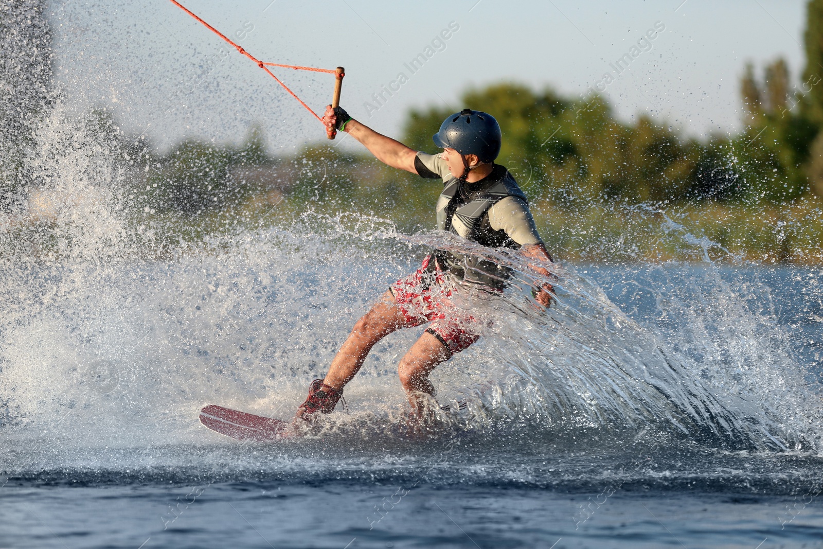 Photo of Teenage boy wakeboarding on river. Extreme water sport