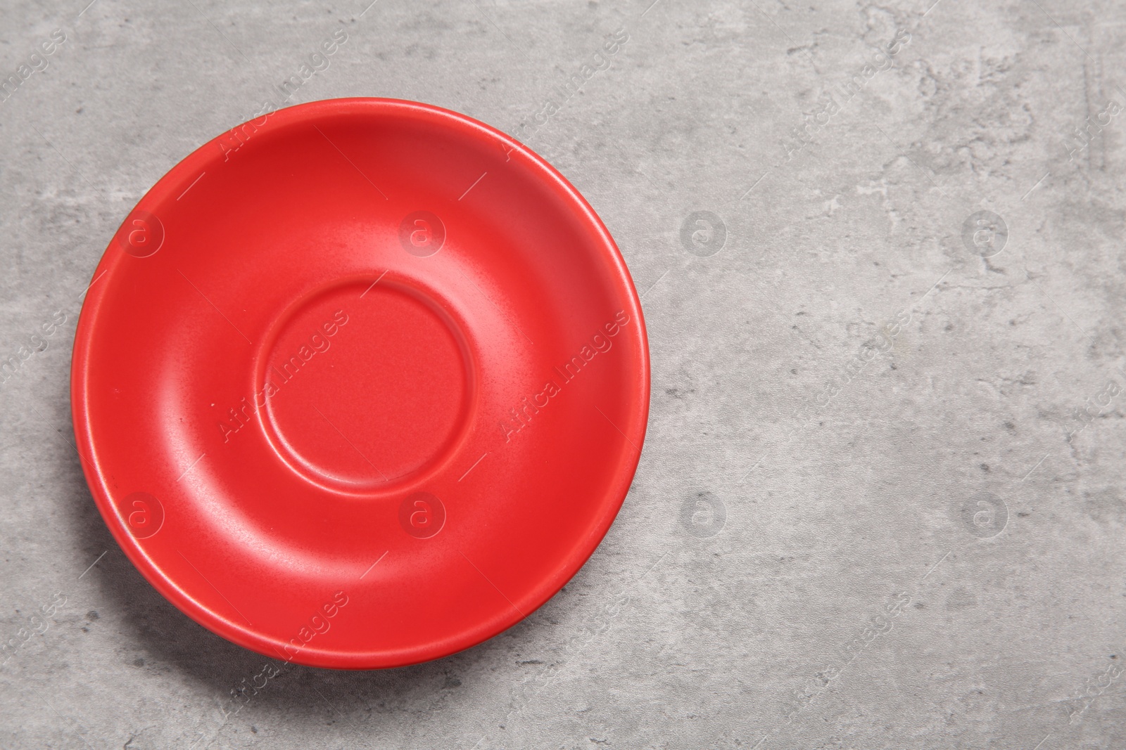 Photo of One red ceramic plate on light grey table, top view. Space for text