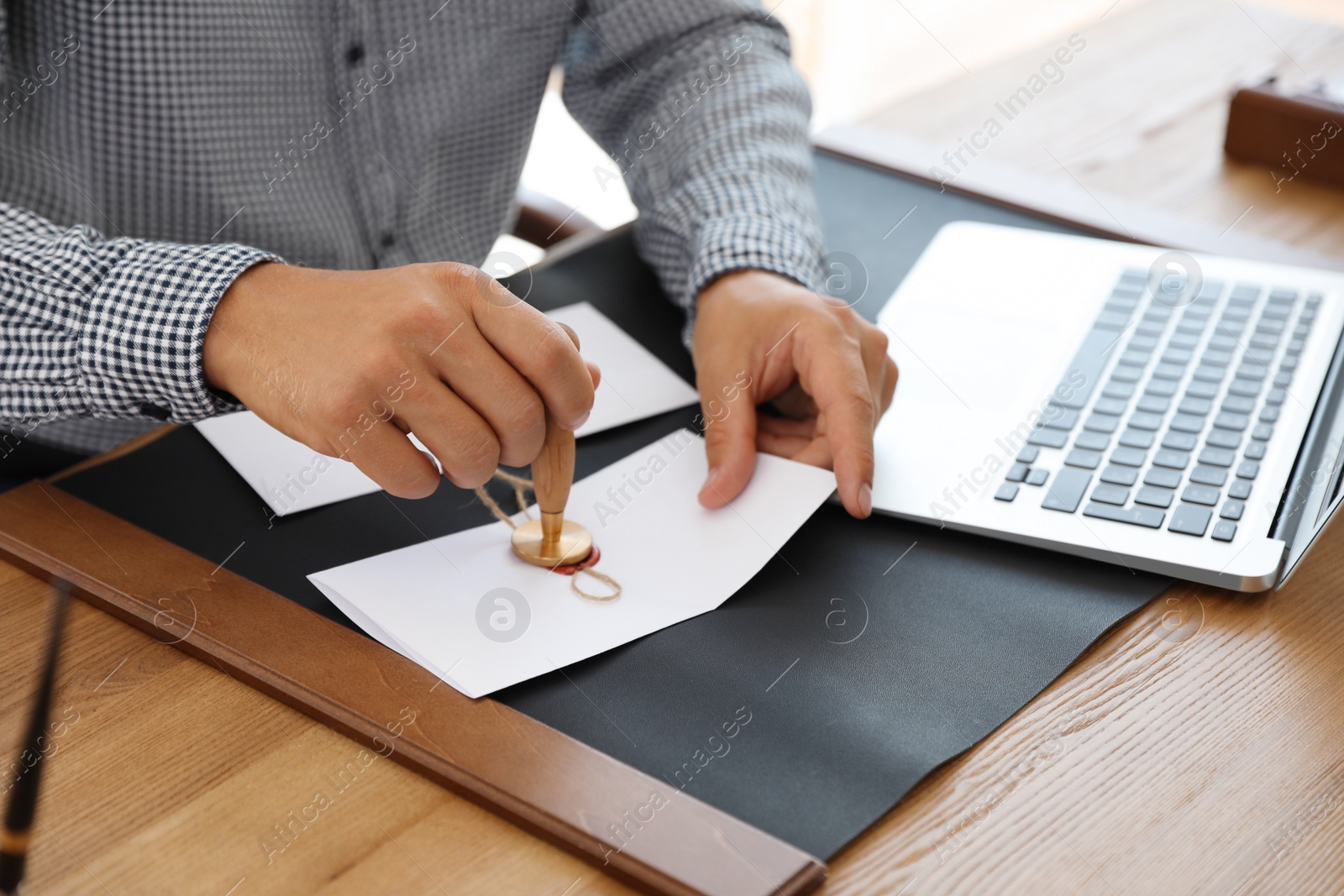 Photo of Male notary stamping document at table in office, closeup