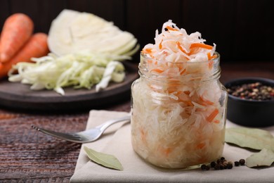Photo of Glass jar of tasty sauerkraut on wooden table, closeup. Space for text