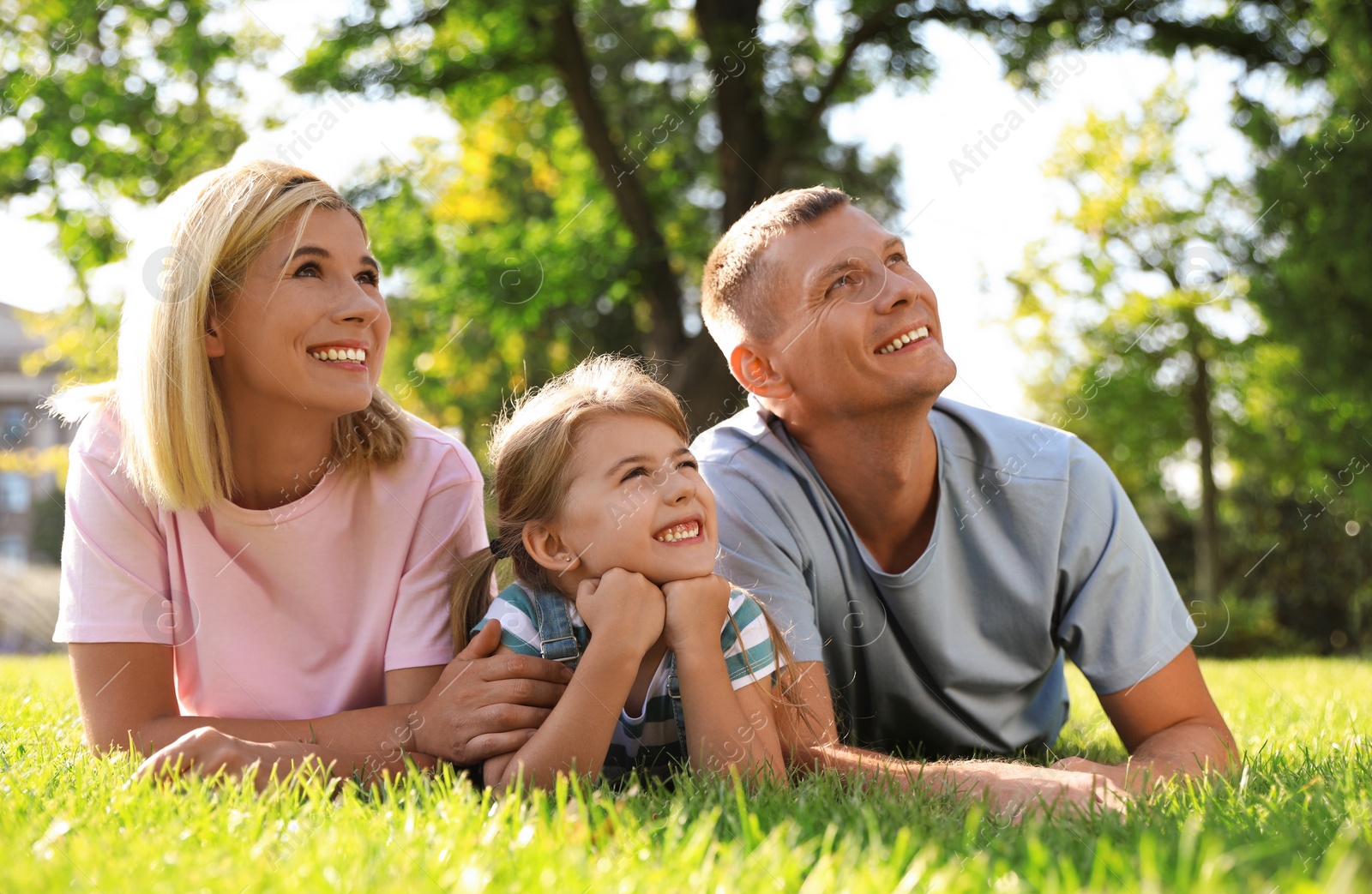 Photo of Happy parents with their child having fun on green grass. Spending time in nature