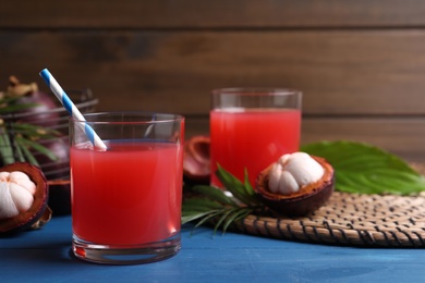 Photo of Delicious fresh mangosteen juice on blue wooden table