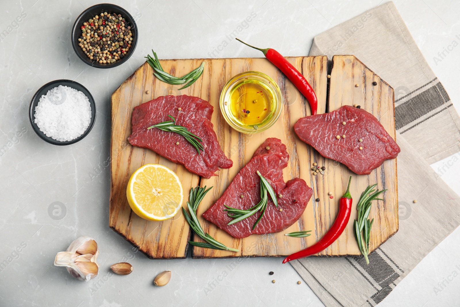 Photo of Fresh raw meat steaks and spices on light grey table, flat lay