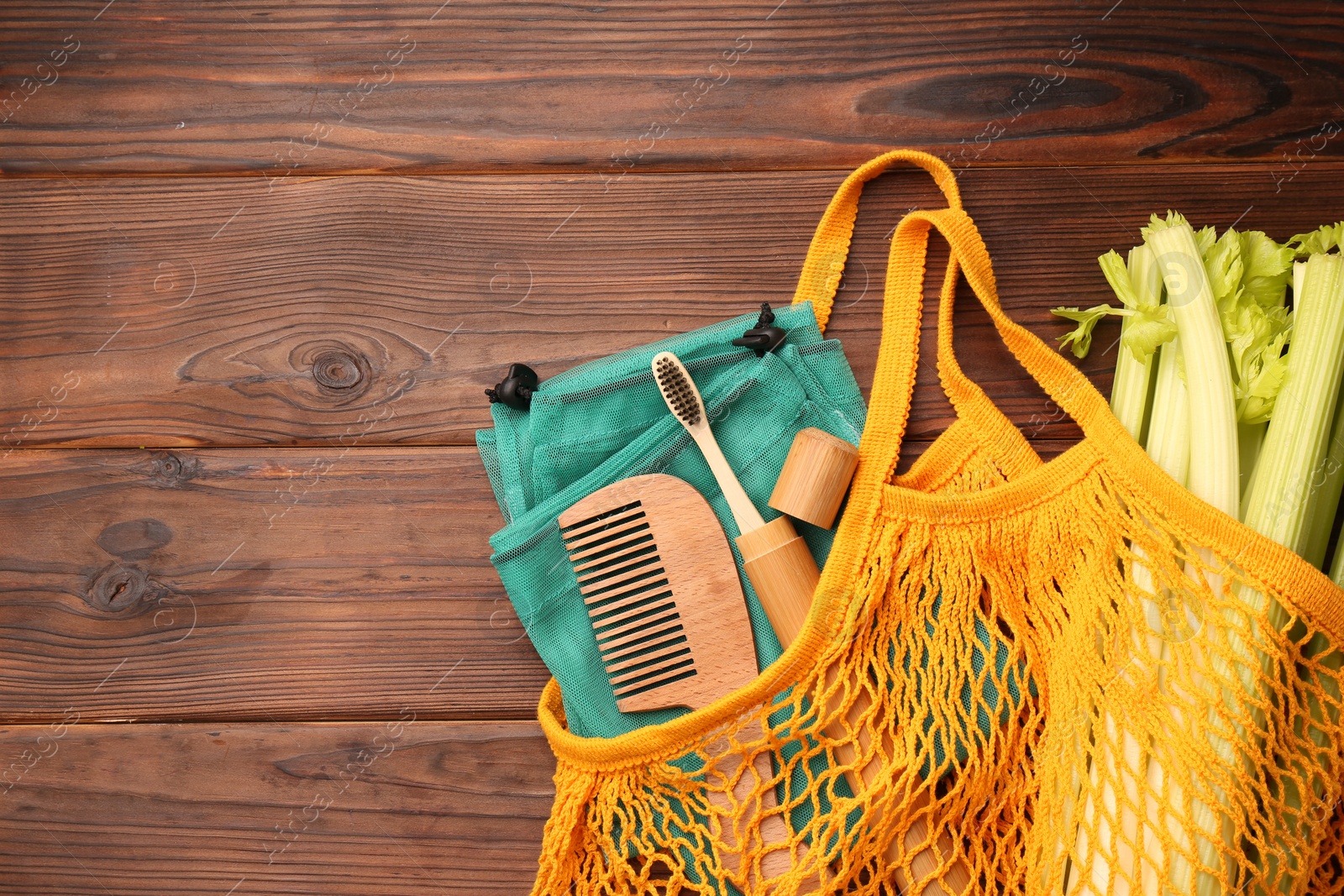 Photo of Fishnet bag with different items on wooden table, top view and space for text. Conscious consumption