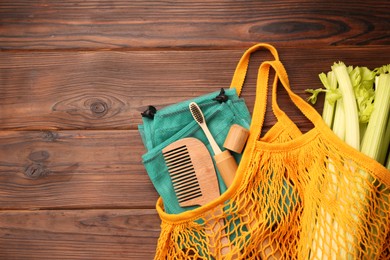 Fishnet bag with different items on wooden table, top view and space for text. Conscious consumption