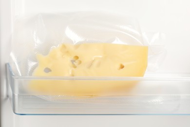 Photo of Vacuum bag with cheese in fridge, closeup. Food storage