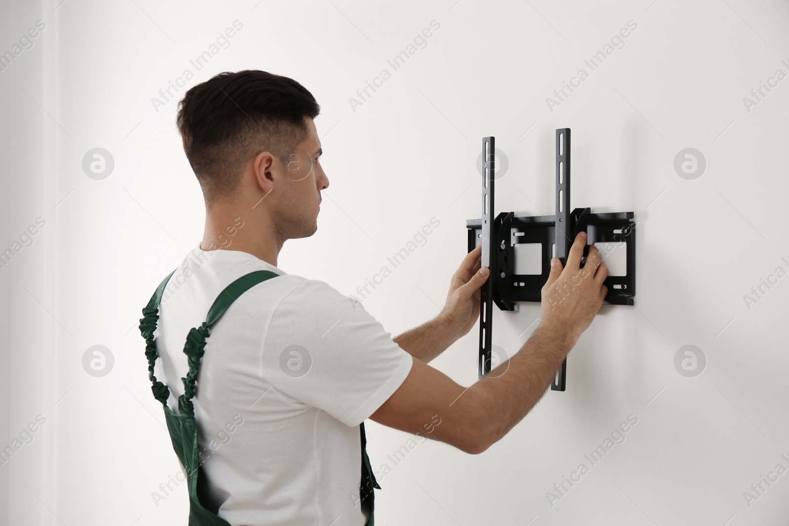 Photo of Professional technician installing TV bracket on wall indoors