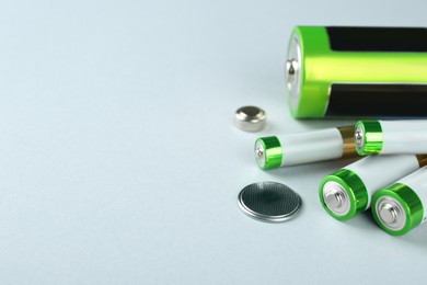 Different types of batteries on light background, space for text