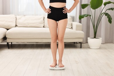 Photo of Woman standing on floor scales at home, closeup