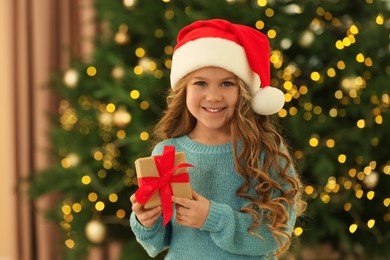 Photo of Happy little girl with Christmas gift at home