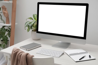 Image of Comfortable workplace at home. Modern computer with blank screen and notebook on white desk. Mockup for design