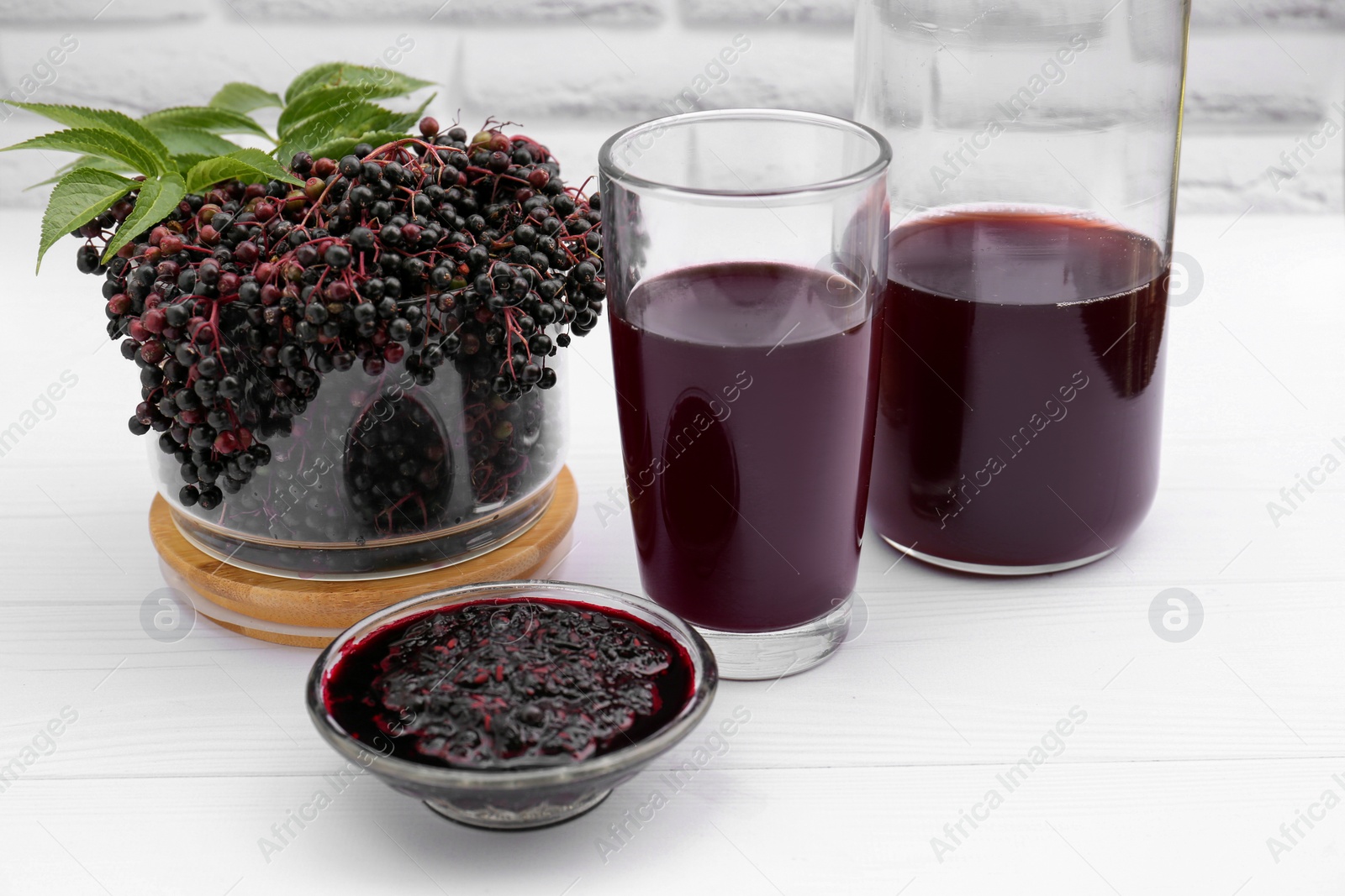 Photo of Elderberry drink and jam with Sambucus berries on white wooden table