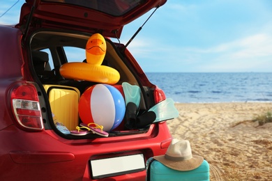 Photo of Red car with luggage on beach. Summer vacation trip