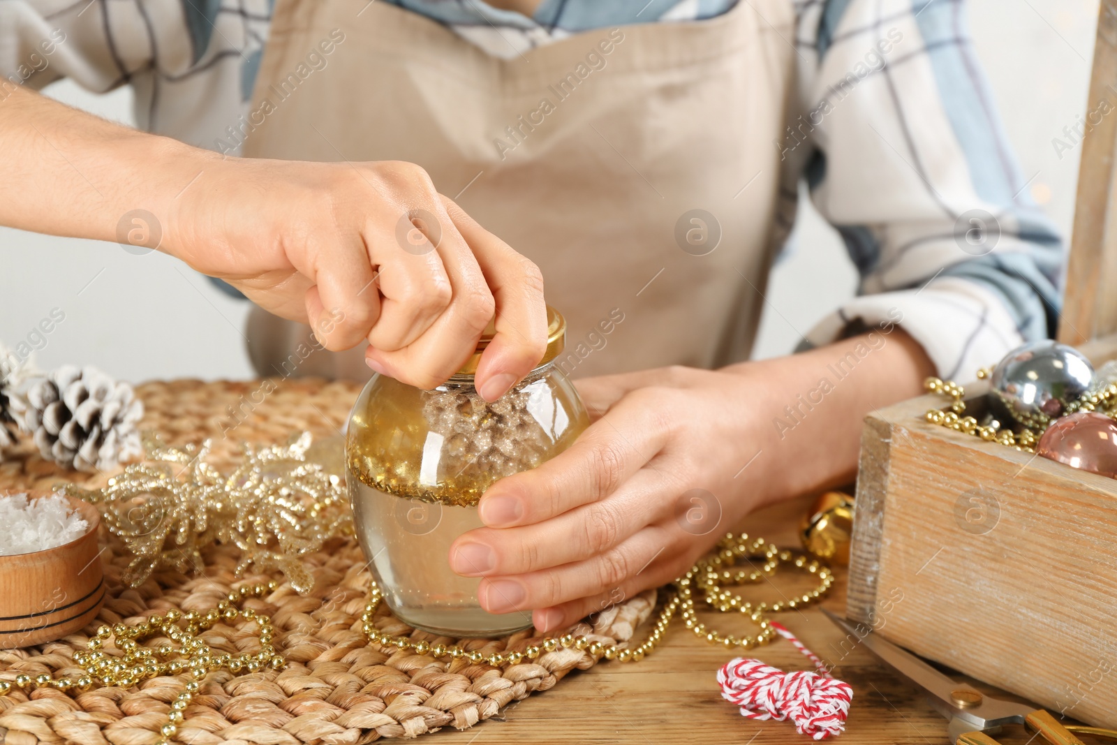 Photo of Woman making snow globe at wooden table, closeup