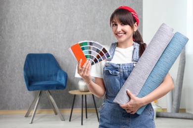 Image of Woman with wallpaper rolls and color selection chart in room