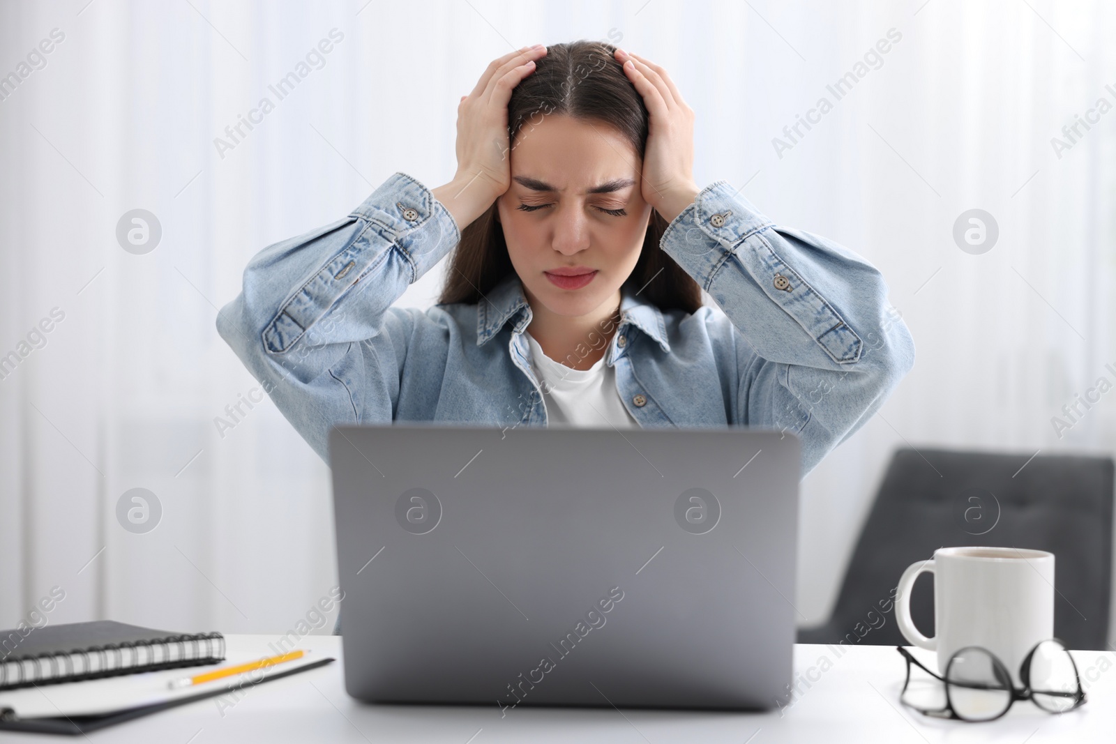 Photo of Woman suffering from headache at workplace in office