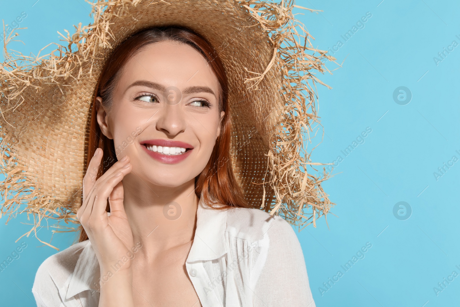 Photo of Beautiful young woman in straw hat on light blue background, space for text