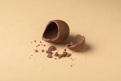 Photo of Broken milk chocolate egg on beige background