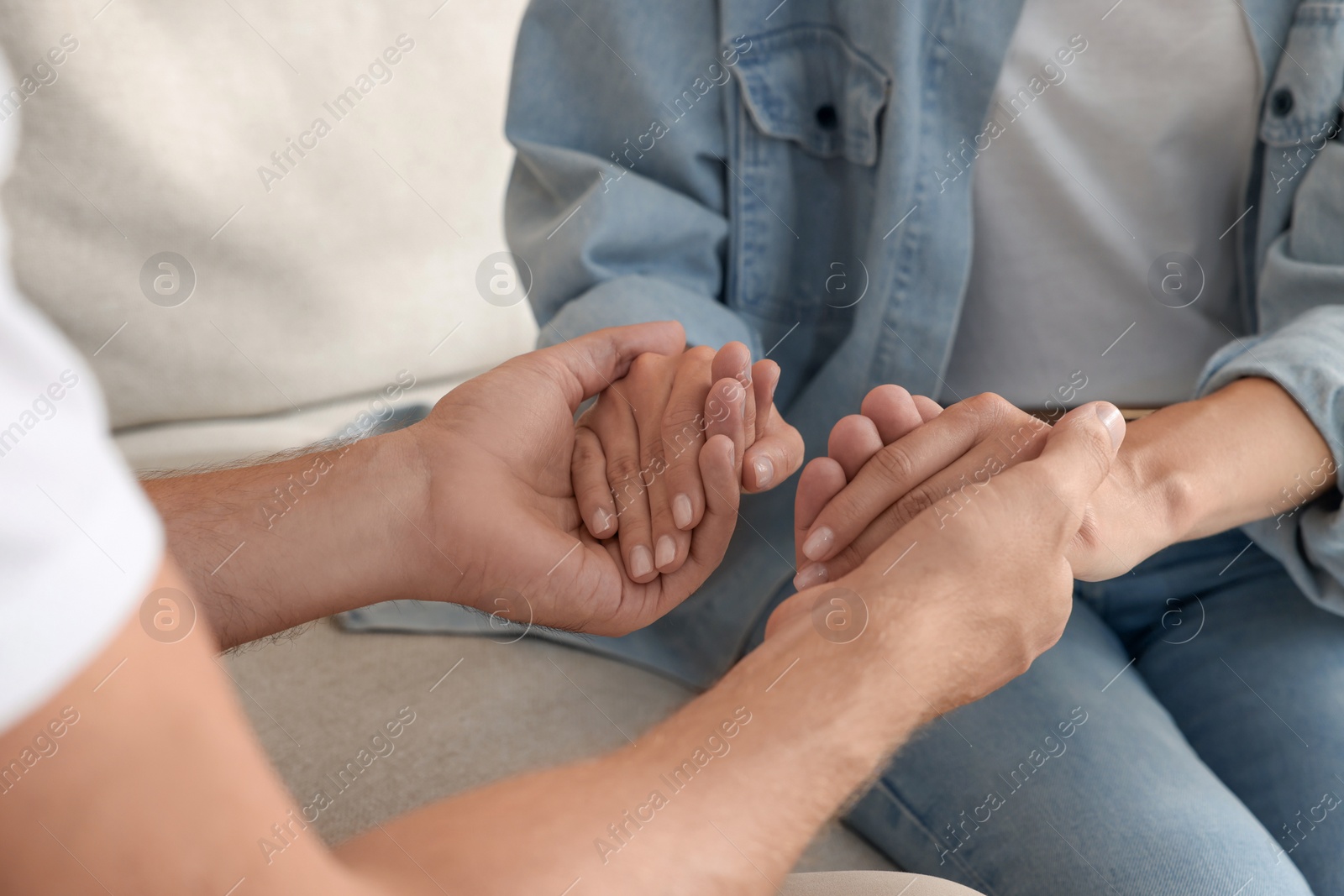 Photo of Religious people holding hands and praying together indoors, closeup