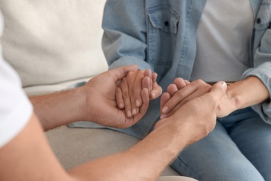 Religious people holding hands and praying together indoors, closeup