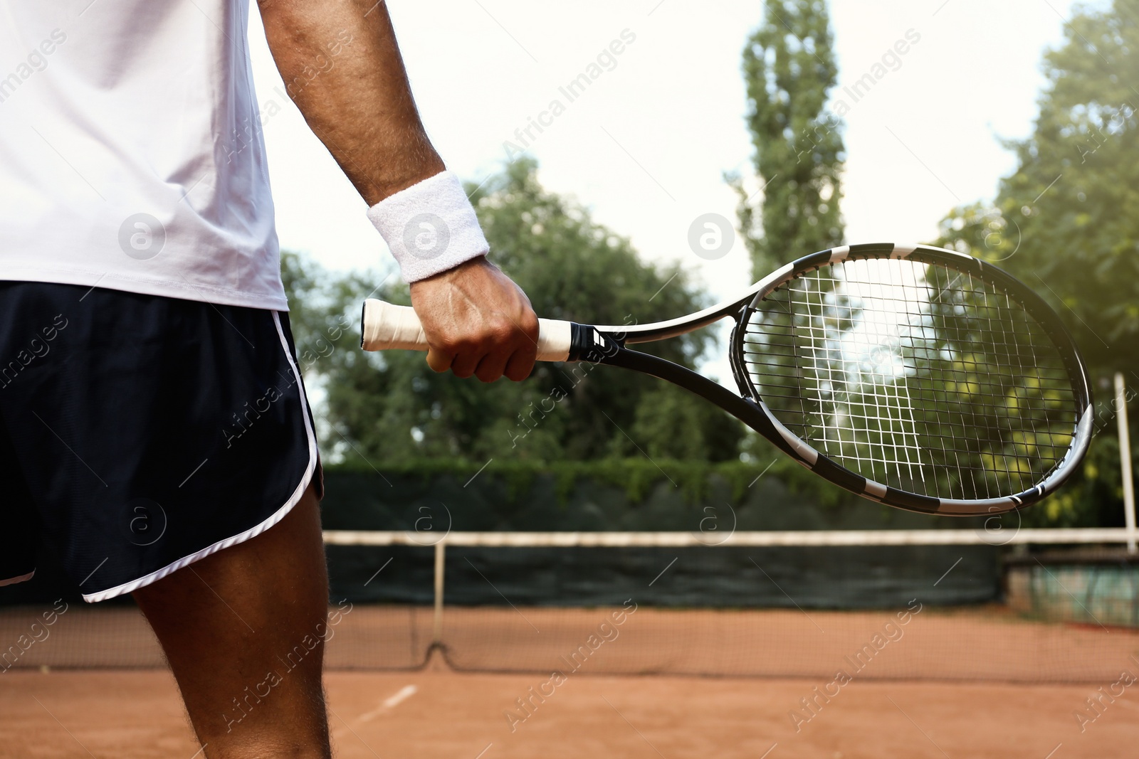 Photo of Sportsman playing tennis at court on sunny day, closeup