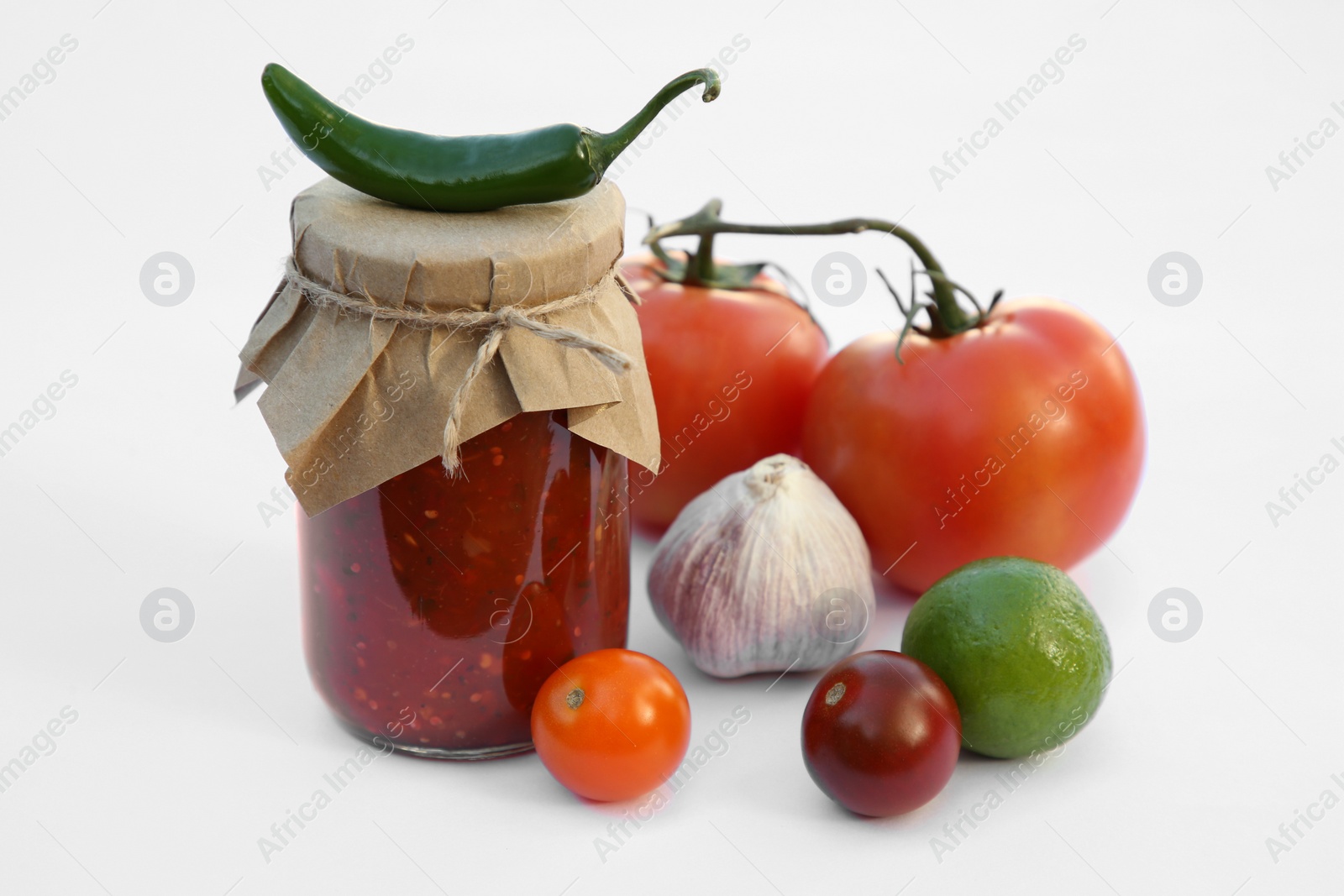 Photo of Jar with delicious salsa sauce and ingredients on white background