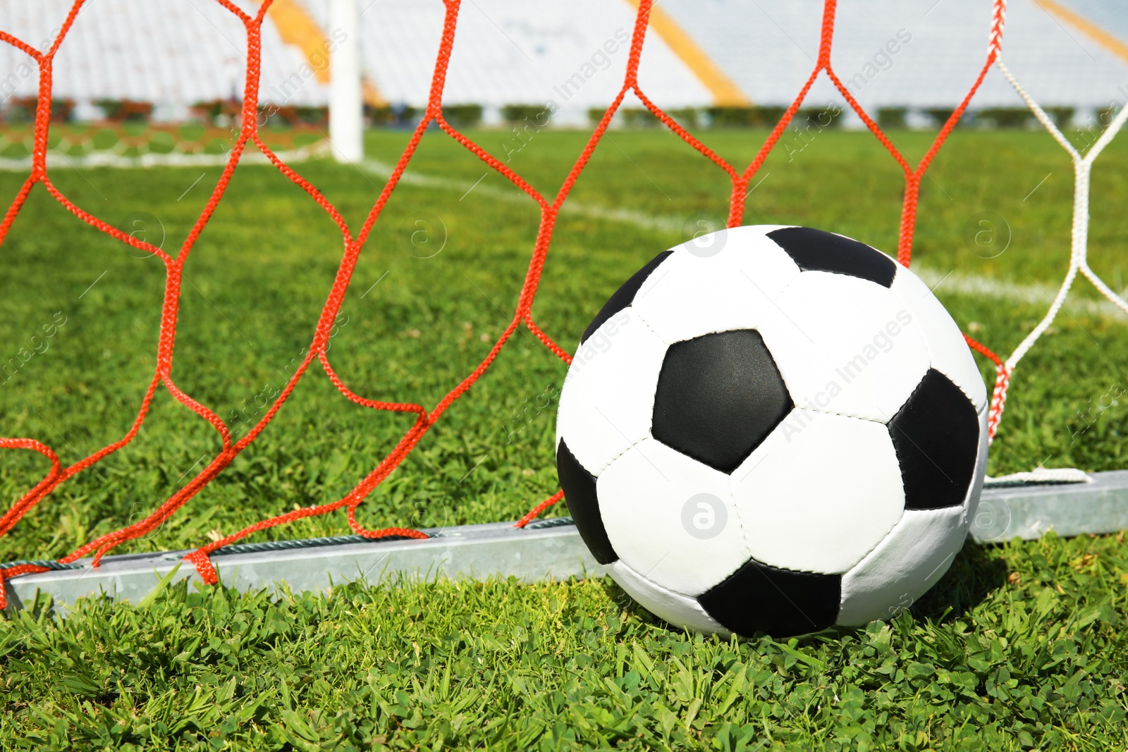 Photo of Soccer ball near net on green football field grass