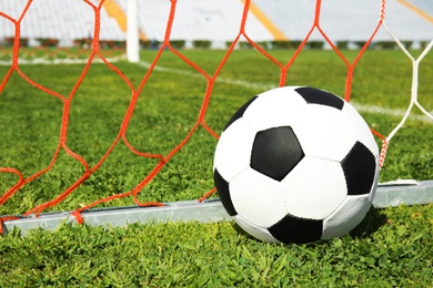 Photo of Soccer ball near net on green football field grass