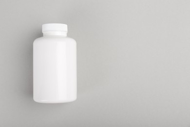 Photo of Blank white pill bottle on light grey background, top view. Space for text