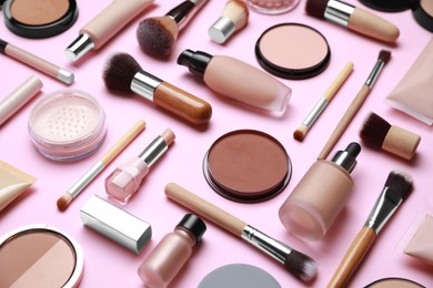 Face powders and other decorative cosmetic products on pink background