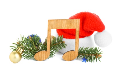 Wooden music note with Santa hat, fir tree branches and Christmas decor on white background