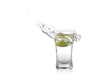 Photo of Splashing Mexican Tequila in shot glass with lime slice isolated on white