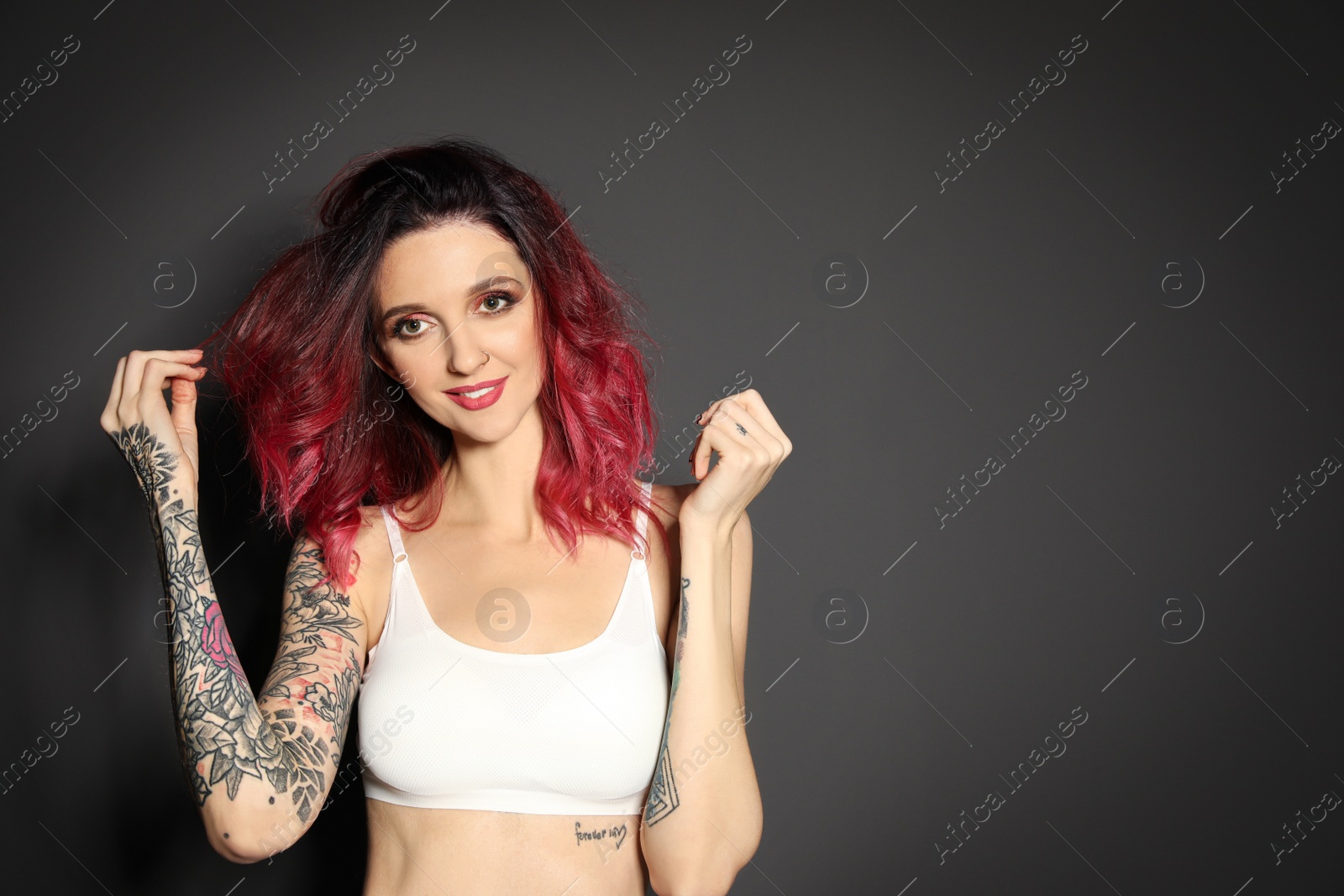 Photo of Beautiful woman with tattoos on body against black background. Space for text