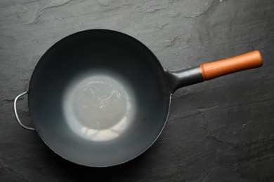 Empty iron wok on black slate table, top view. Chinese cookware