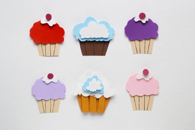 Photo of Different paper cupcakes on white background, flat lay