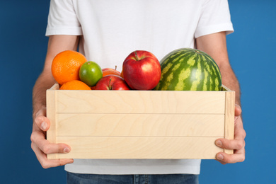 Courier with fresh products on blue background, closeup. Food delivery service