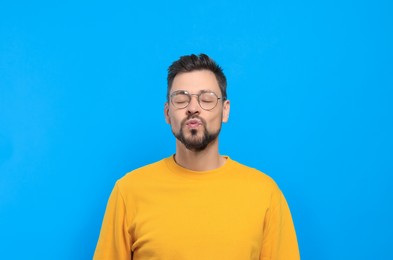 Photo of Handsome man blowing kiss on light blue background