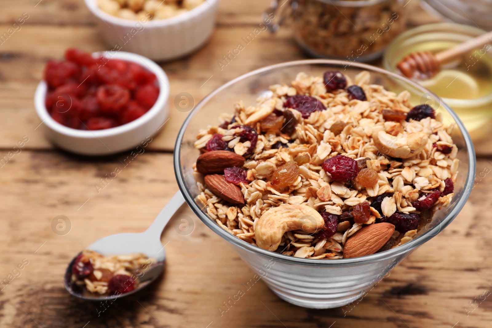 Photo of Tasty granola served with nuts and dry fruits on wooden table, closeup