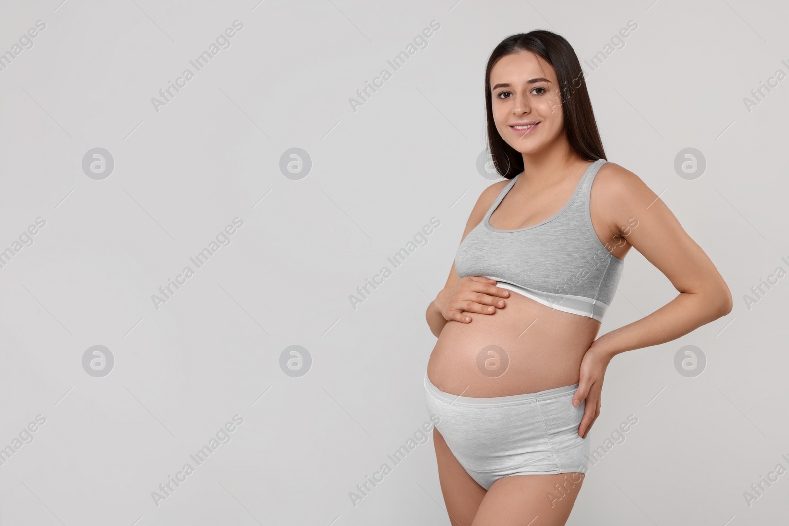 Photo of Beautiful pregnant woman in comfortable maternity underwear on grey background, space for text