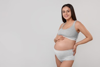 Photo of Beautiful pregnant woman in comfortable maternity underwear on grey background, space for text