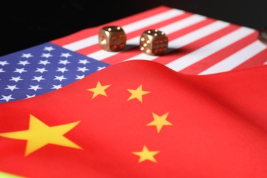 USA and China flags with dice on black table. International relations