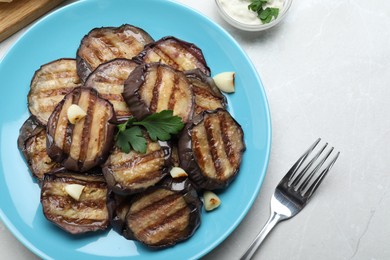 Delicious grilled eggplant slices served on light table, flat lay