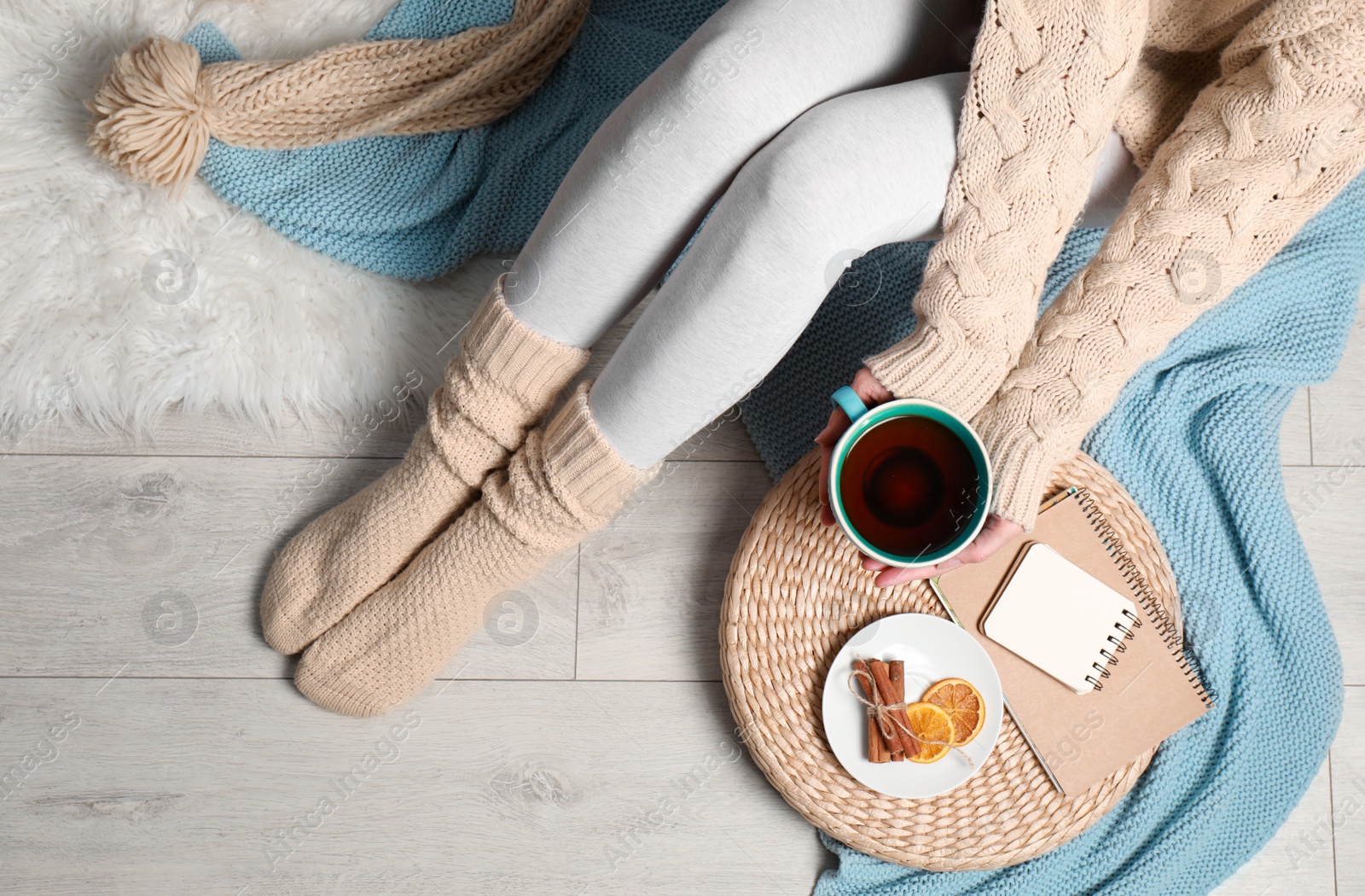 Photo of Woman and cup of hot winter drink on floor at home, top view