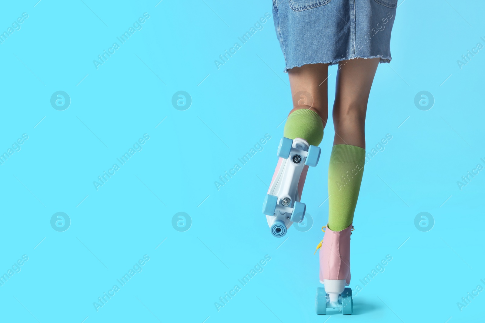 Photo of Woman with vintage roller skates on color background, closeup. Space for text